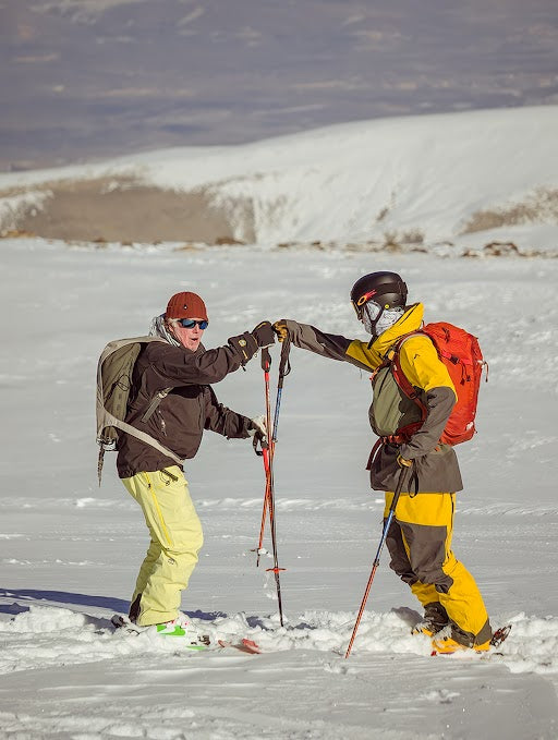Two skiers share a fist bump at the base of a Turkish mountainside.