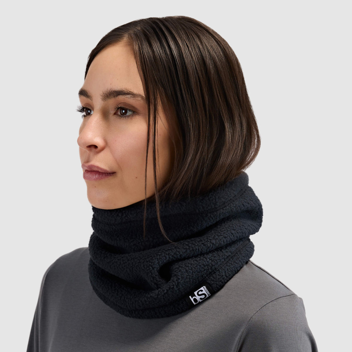 BlackStrap Caldera Sherpa Fleece Tube Neck Gaiter Black worn by a woman around the neck like a scarf #color_black