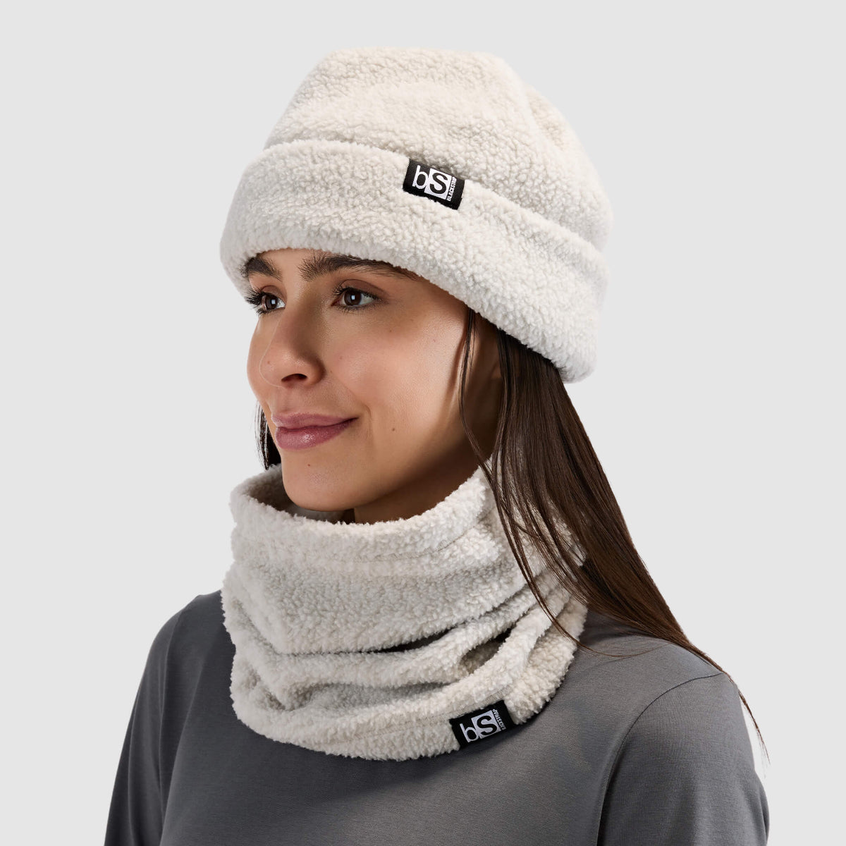 BlackStrap Caldera Sherpa Fleece Tube Neck Gaiter Inprint Ash worn by a woman with a beanie and worn around the neck like a scarf #color_inprint-ash