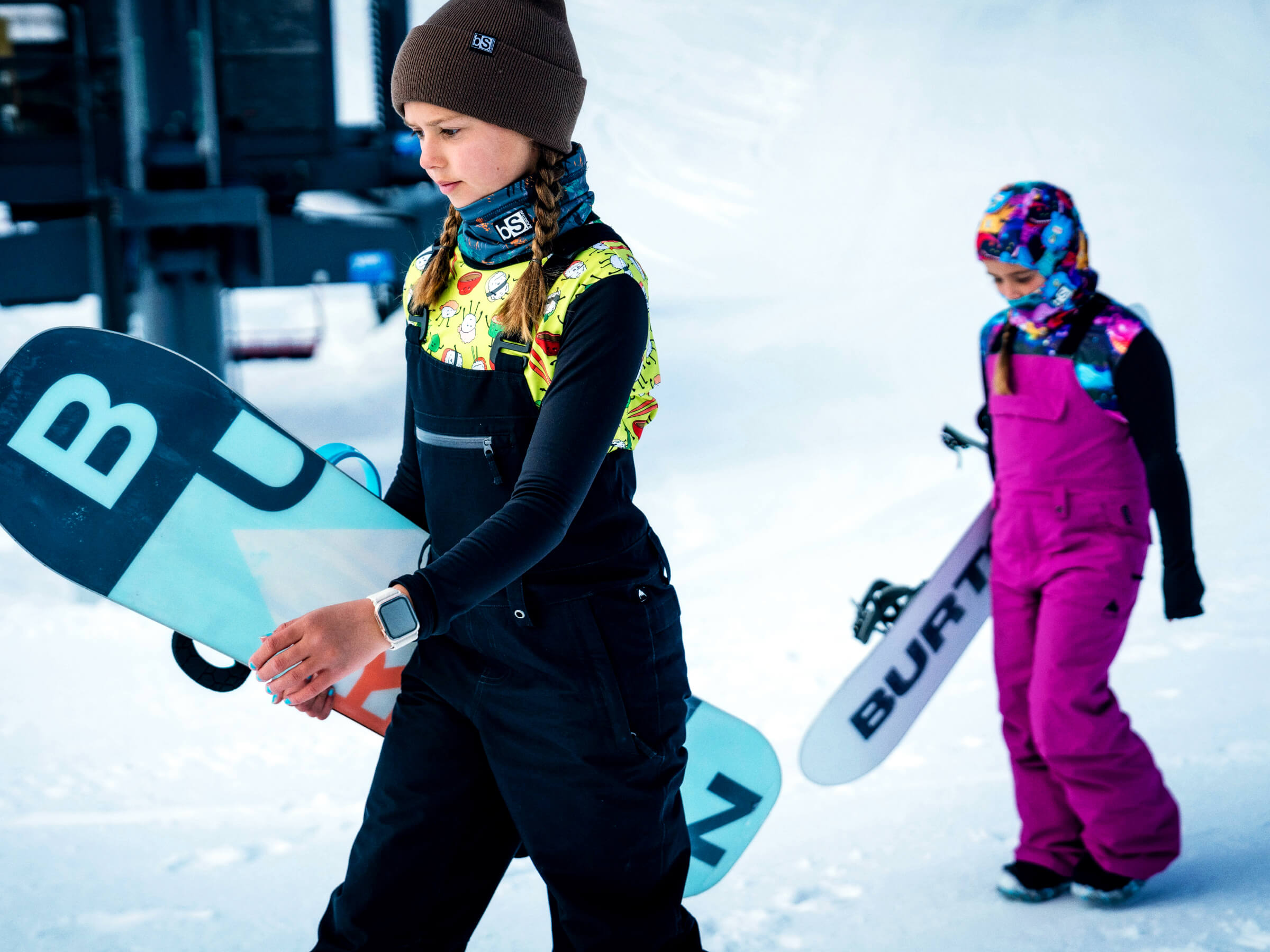 Two kids walking up to the lift line in their base layer crew tops designed for a perfect spring lap day.