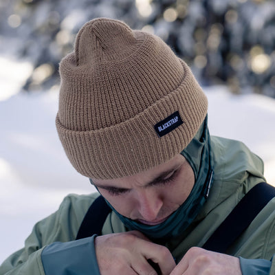 Man in a beanie and bibs preparing for a day on the slopes.