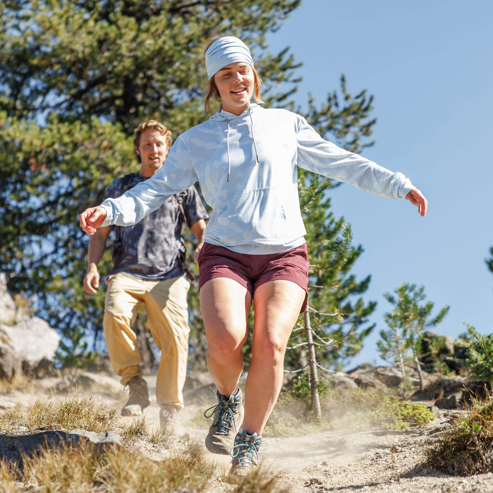Woman hiking down a dusty mountain trail wearing the BlackStrap Women's Aspect Hoodie Long Sleeve