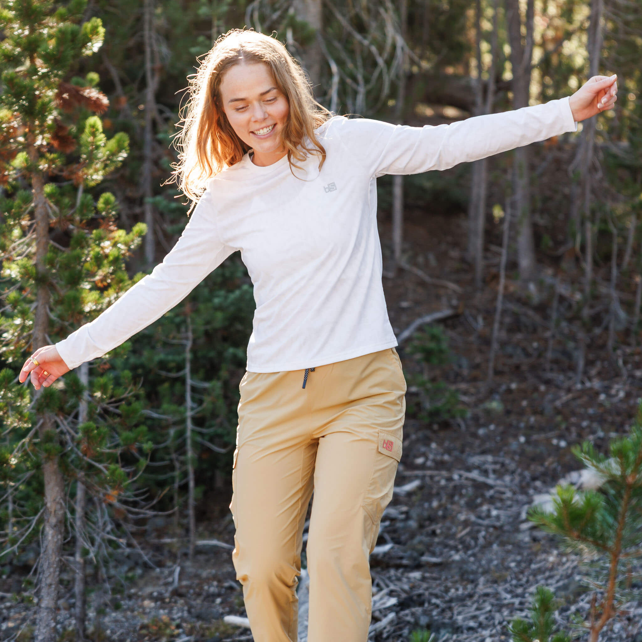 Woman balancing with arms outstretched on a forest trail wearing the BlackStrap Women's Aspect Long Sleeve