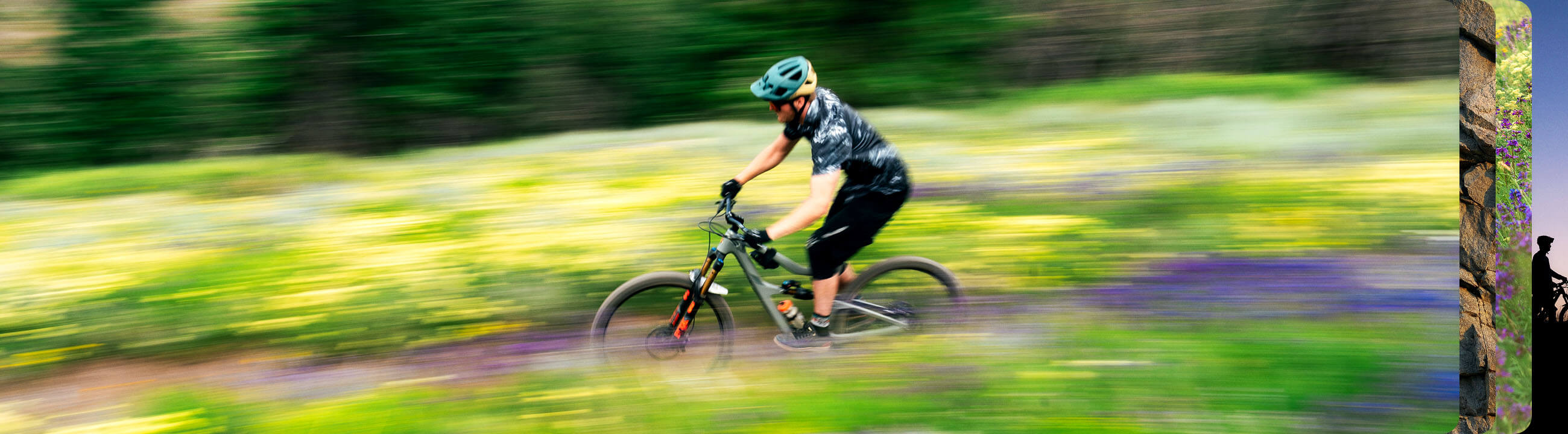 A person on a purple mountain bike performs a mid-air trick against a backdrop of trees and a partly cloudy sky.