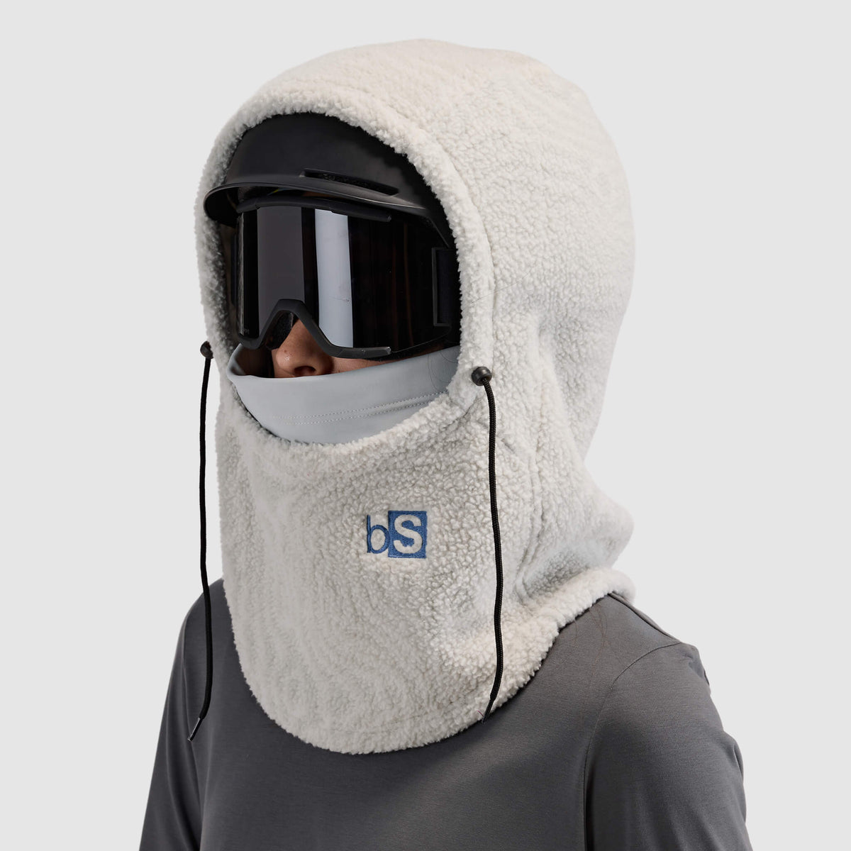 BlackStrap Caldera Hood Sherpa Fleece Overhood Inprint Ash worn by a woman wearing a helmet and ski goggles #color_inprint-ash