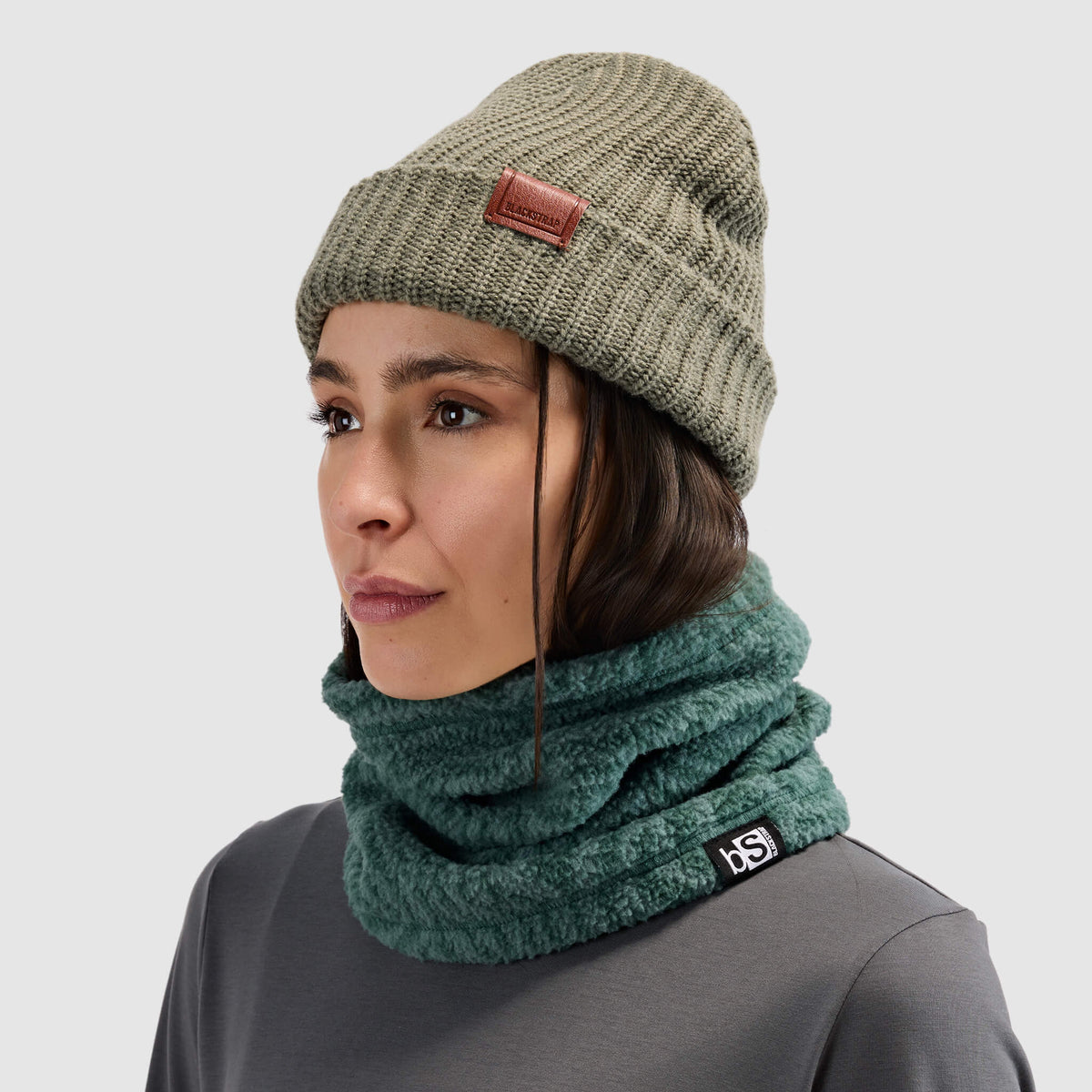 BlackStrap Caldera Sherpa Fleece Tube Neck Gaiter Inprint Obsidian worn by a woman with a beanie and worn around the neck like a scarf #color_inprint-obsidian