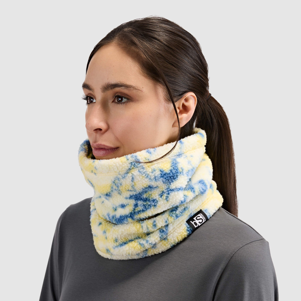 BlackStrap Caldera Sherpa Fleece Tube Neck Gaiter Pulse Orion worn by a woman around the neck like a scarf #color_pulse-orion