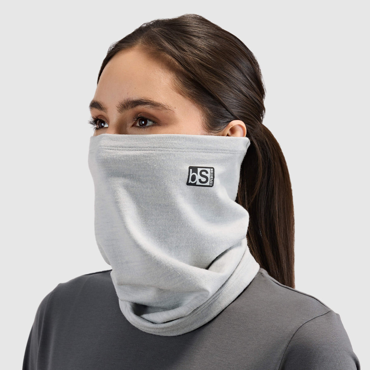BlackStrap Merino Expedition Tube Neck Gaiter in Ash worn up over the nose like a face mask by a woman