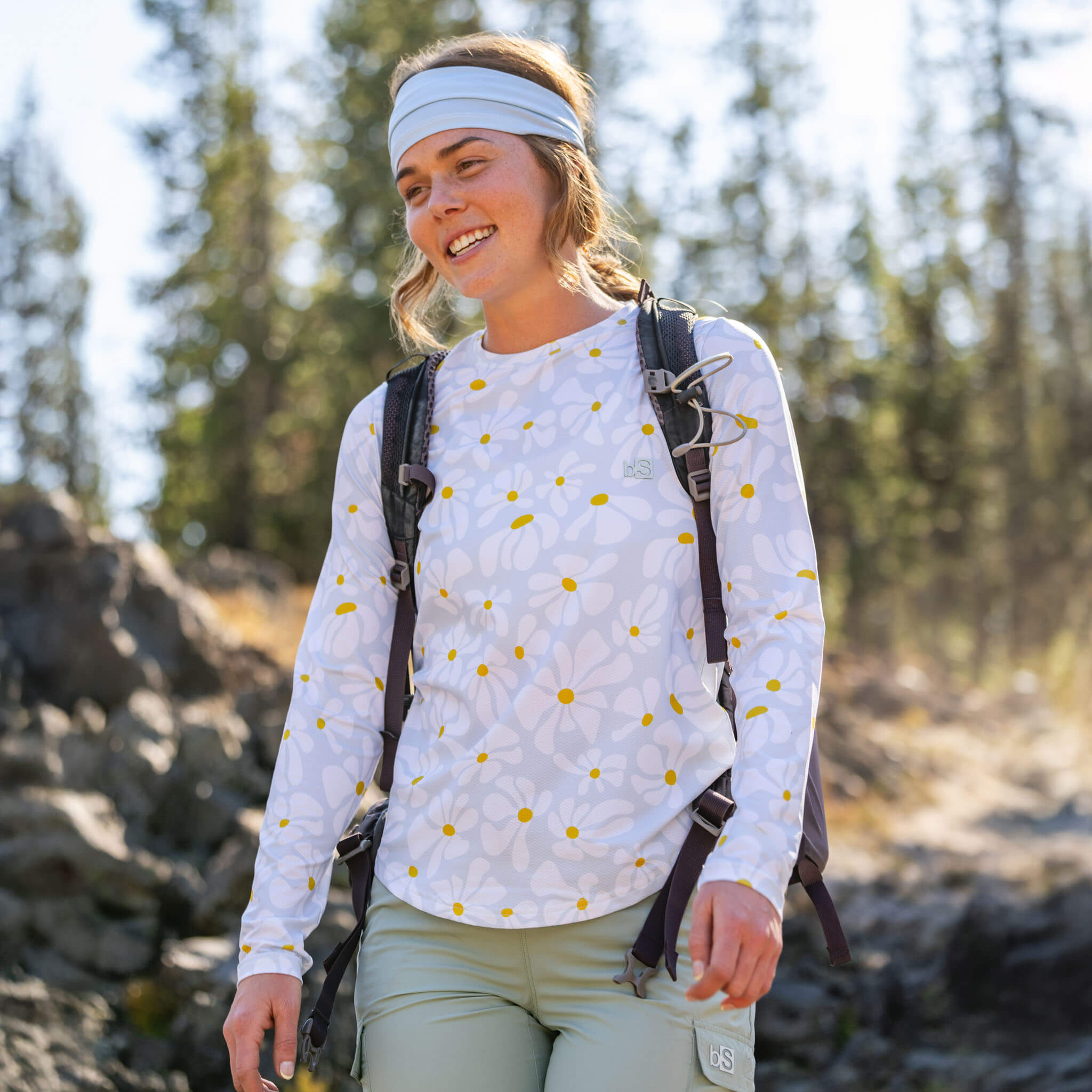 Woman hiking with a backpack on a rocky trail wearing the BlackStrap Women's Voyage Crew Long Sleeve 