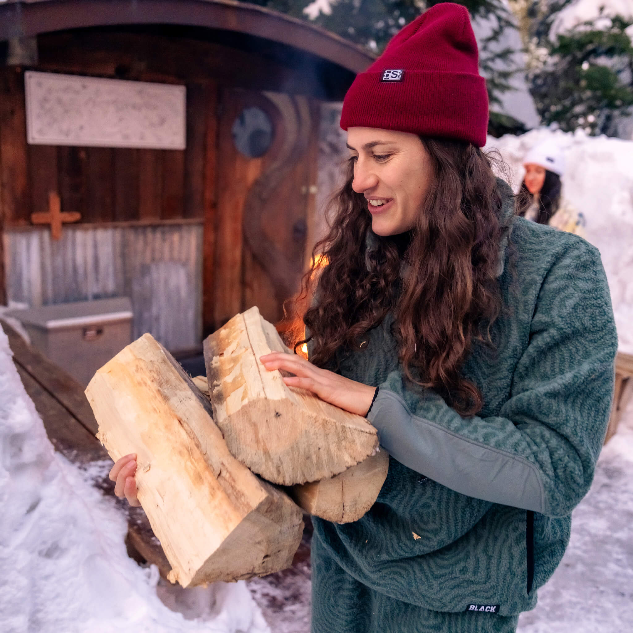 Female wearing the blackstrap caldera sherpa fleece at a mountain cabin carrying firewood.